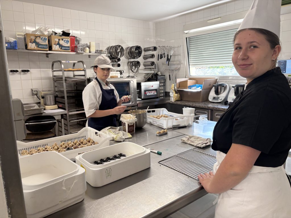 A Dieuze, ils sont 6 jeunes cuisiniers de terminale bac pro cuisine à s’affairer. Objectif de ce vendredi : terminer toutes les sauces, les tartelettes, pour qu’il ne reste plus que la mise en place lundi midi. Au menu : gravelax de truite, paleron de veau confit et un dessert noisette et chocolat au lait. Après avoir pris contact avec l’évêque de Metz Mgr Philippe Ballot, l’établissement a souhaité se positionner pour l'événement. Daniel Trichies, directeur du site de la Providence de l’ensemble Saint Clément est fier de gérer la manifestation au grand séminaire ce lundi. Il précise “nous avons eu un protocole, nous avons proposé des produits du terroir. C’est un événement dont on se souviendra à vie”. Entre la cuisine et les salles, 40 élèves de Dieuze seront à Metz lundi Les élèves eux s’appliquent. Amy Durmeyer, 17 ans, se charge de pocher la mousseline au praliné pour le dessert, Alexis Davaux coupe les câpres; pour lui “il y a un peu de stress mais les gestes sont maîtrisés”. En plus de ce groupe de cuisiniers, à Metz, au grand séminaire les tables sont dressées et les détails soignés. Ilyes Cherdouh élève de terminale raconte : “nous avons repassé les nappes et ensuite il faut mettre les couteaux d’entrée, de dessert”. Emma Sattler est dans la même classe, elle a appris il y a deux semaines qu’elle serait une des 6 élèves à servir le pape lundi : “c’est une grande opportunité, c’est quelqu’un d’important”. Chaque détail est scruté Sous l'œil concentré de la professeure de service en salle, Emma Gross, les élèves vérifient chaque détail, elle précise “ils sont tous allés chez le coiffeur et ils ont même acheté des blazers pour l’occasion”. Six élèves, deux enseignants et le personnel professionnel de la maison Loiseau pourront donc servir le pape lundi 28 septembre. Entre les cuisines et les salles, plus de 40 élèves de Dieuze seront sur place. Si tous ne pourront pas apporter le déjeuner de Léon XIV, tous espèrent au moins faire une photo de groupe avec le Saint Père.